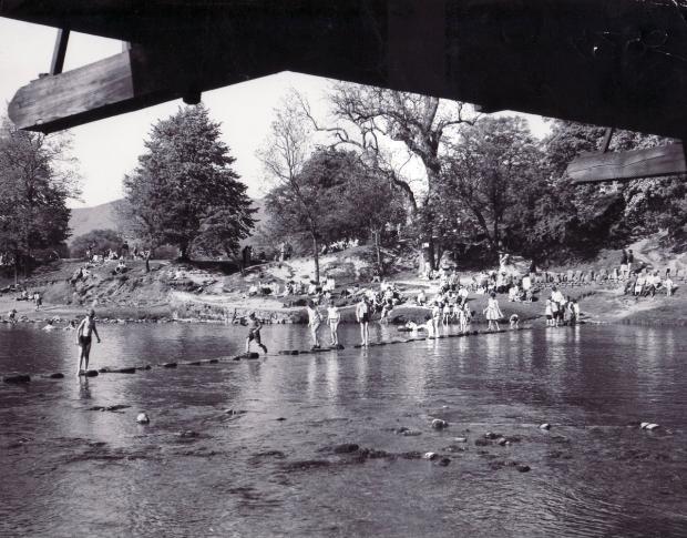 Bradford Telegraph and Argus: Children crossing the stepping stones at Bolton Abbey in the long summer holiday in 1963